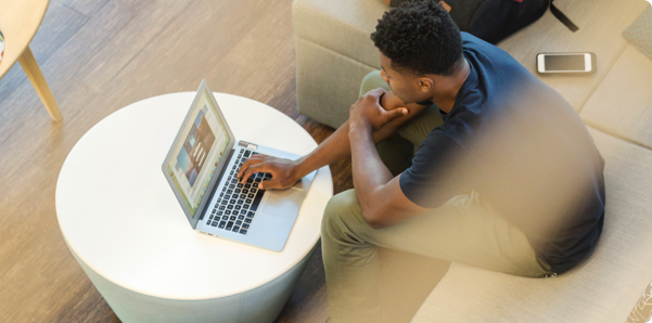 man using gray laptop while sitting on beige sofa 1251862